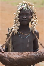ETHIOPIA, South Omo Valley, Mursi Tribe, Girl with animal skin bag.