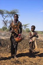 ETHIOPIA, Lower Omo Valley, Tumi, "Dombo village, Child watching Hamer lady stirring cows bood