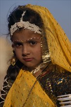 INDIA, Rajasthan, Jaisalmer, Portrait of a young girl wearing yellow with make up and jewellery an