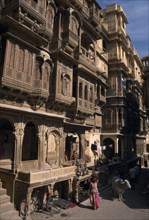 INDIA, Rajasthan, Jaisalmer, Patwon ki Haveli exterior with people and cattle seen on the path at