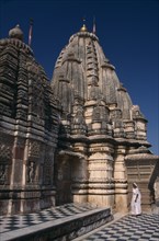 INDIA, Rajasthan, Osian, Sachiya Mata Temple with a woman dressed in white standing at the base