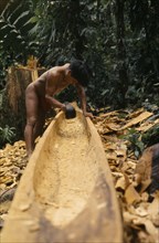COLOMBIA, Choco, Embera Indigenous People, Embera man using axe or adze .  to hollow out dug out