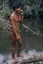 COLOMBIA, North West Amazon, Tukano Indigenous People, Barasana headman Bosco stands on log at