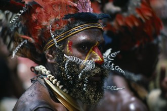 PAPUA NEW GUINEA, Chimbu, Head and shoulders portrait of man wearing traditional head-dress of red
