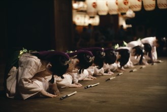 JAPAN, Honshu, Kyoto, During the Gion festival line of young girls finish their dance with a deep