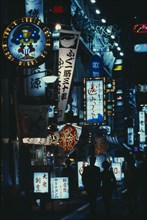 JAPAN, Honshu, Tokyo, "City street scene at night with illuminated neon signs advertising bars,