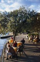 ITALY, Piedmont, Pallanza, Lake Maggiore.  People enjoying lakeside views sitting at cafe tables