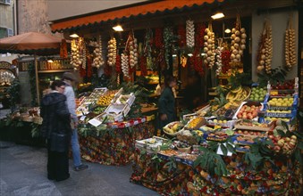 SWITZERLAND, Ticino, Lugano, Member of staff and customers outside fruit and vegetable stall with