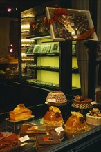 SWITZERLAND, Ticino, Lugano, Cakes and chocolate displayed in window of cafe.