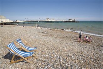 ENGLAND, West Sussex, Worthing, View across beach towards the pier with blue and white deckchairs