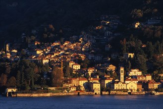 ITALY, Lombardy, Lake Como, Torno.  View across Lake Como towards town spread across hillside in