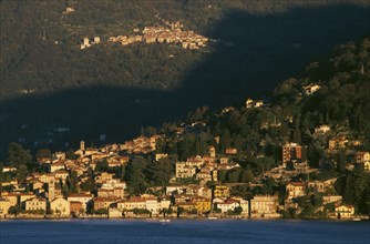 ITALY, Lombardy, Lake Como, Torno.  View across Lake Como towards town spread across hillside in