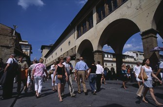 ITALY, Tuscany, Florence, Ponte Vecchio Bridge with visitors walking along street lined with shops