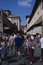 ITALY, Tuscany, Florence, Ponte Vecchio Bridge. People walking along street lined with shops and