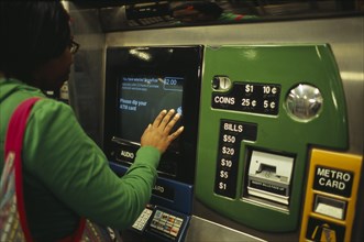 USA, New York, New York City, Young woman using metro ticket machine to purchase ticket.