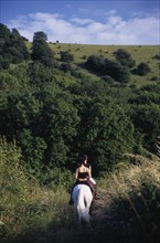ENGLAND, East Sussex, Plumpton, Horse riders on a bridlepath at the foot of the South Downs.