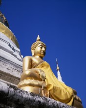 THAILAND, North, Chiang Mai, Seated golden Buddha statue robed in gold silk.