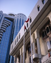 UAE, Dubai, "Two flag poles in front of contrasting styles of architecture, modern, mainly glass