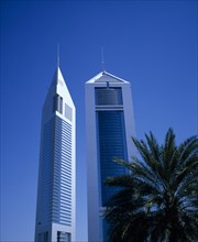 UAE, Dubai, Emirates Towers with palm tree in foreground.