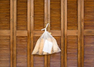 MALTA, Saint Julians, Plastic bag containing loaves of fresh bread tied to the handle of wooden