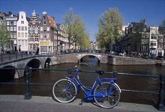 HOLLAND, Noord Holland, Amsterdam, Blue bicycle leaning against a railing on bridge with