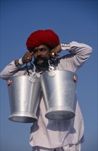 INDIA, Rajasthan, Bikaner, Rajput man lifting buckets of water with his moustache during the Camel