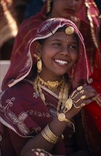 INDIA, Rajasthan, Bikaner, Portrait of a young girl dancer smiling wearing traditional jewellery at