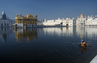 INDIA, Punjab, Amritsar, Sikh devotee taking a ceremonial dip in the tank at the Golden Temple