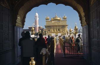 INDIA, Punjab, Amritsar, Entrance arch to the Golden Temple with people walking along red carpet