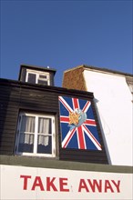 ENGLAND, East Sussex, Hastings, Fish and Chips shop take away frontage with a Union Jack flag sign.