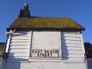 ENGLAND, East Sussex, Hastings, East Beach Street sign on white wooden building