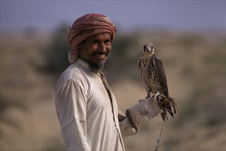 SAUDI ARABIA, Bedouin, Falconry, Bedouin man holding falcon on his wrist.