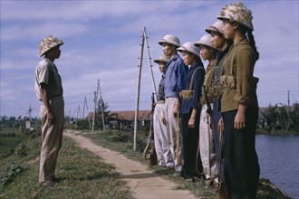 VIETNAM, North , War, Line of male and female Viet Cong soldiers standing in front of superior