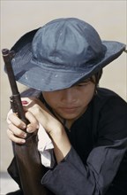 VIETNAM, South, Mekong Delta, Civil Defence girl soldier leaning on gun.