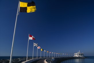 UAE, Dubai, Jumeirah Beach.  Curving marina wall and line of flags.