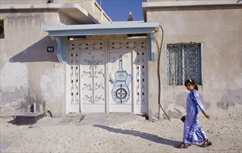 UAE, Dubai, Bur Dubai , Young girl passing building with carved and decorated doorway.  Sheikh