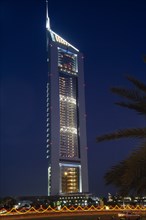 UAE, Dubai , Emirates Tower illuminated at night with coloured lights and passing car in the