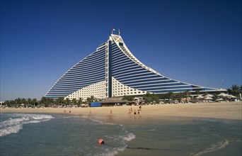 UAE, Dubai , Jumeirah Beach Hotel with people on private beach in foreground.
