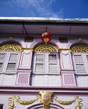 MALAYSIA, Penang, Georgetown, Pink and gold painted shopfront with wooden window shutters and red