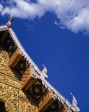 THAILAND, North, Chiang Mai, Detail of highly decorated temple roof with painted carvings of naga