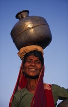 INDIA, Karnataka, Badami, Woman carrying water pot on her head.