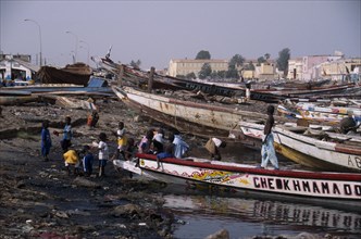 SENEGAL, St Louis, Children playing on shore next to beached boats.