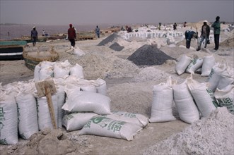 SENEGAL, Lac Rose, Bags of salt on salt flats with workers behind.