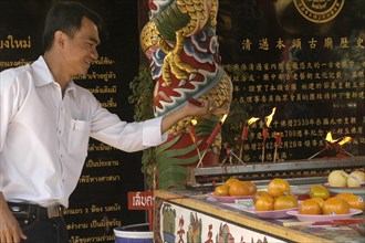 THAILAND, North, Chiang Mai, "Chinese New Year celebrations. A worshiper lighting joss sticks at a