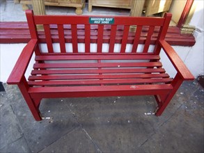 ENGLAND, East Sussex, Hastings, Red wooden bench with a Smokers Rest plaque