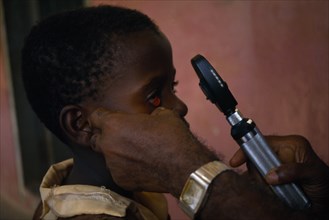 GHANA, Koforidua, Child having eye examination by Doctor using a ophthalmoscope.