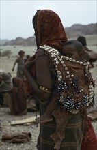 ETHIOPIA, Danakil , People, Mother carrying baby on her back in leather sling decorated with beads