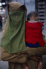 BANGLADESH, Khulna, Char Kukuri Mukuri, Muslim woman wearing full veil and carrying baby against