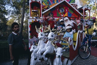 MEXICO, Mexico City, Children visiting Father Christmas in his sleigh in Mexico City Park
