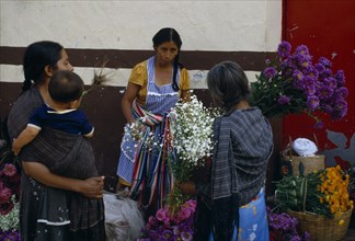 MEXICO, Guerrero, Woman vendor and customers at flower market stall.